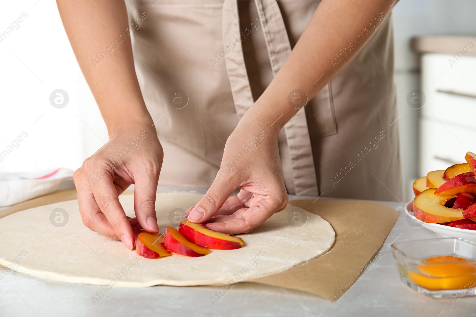 Photo of Woman making peach pie at kitchen table, closeup