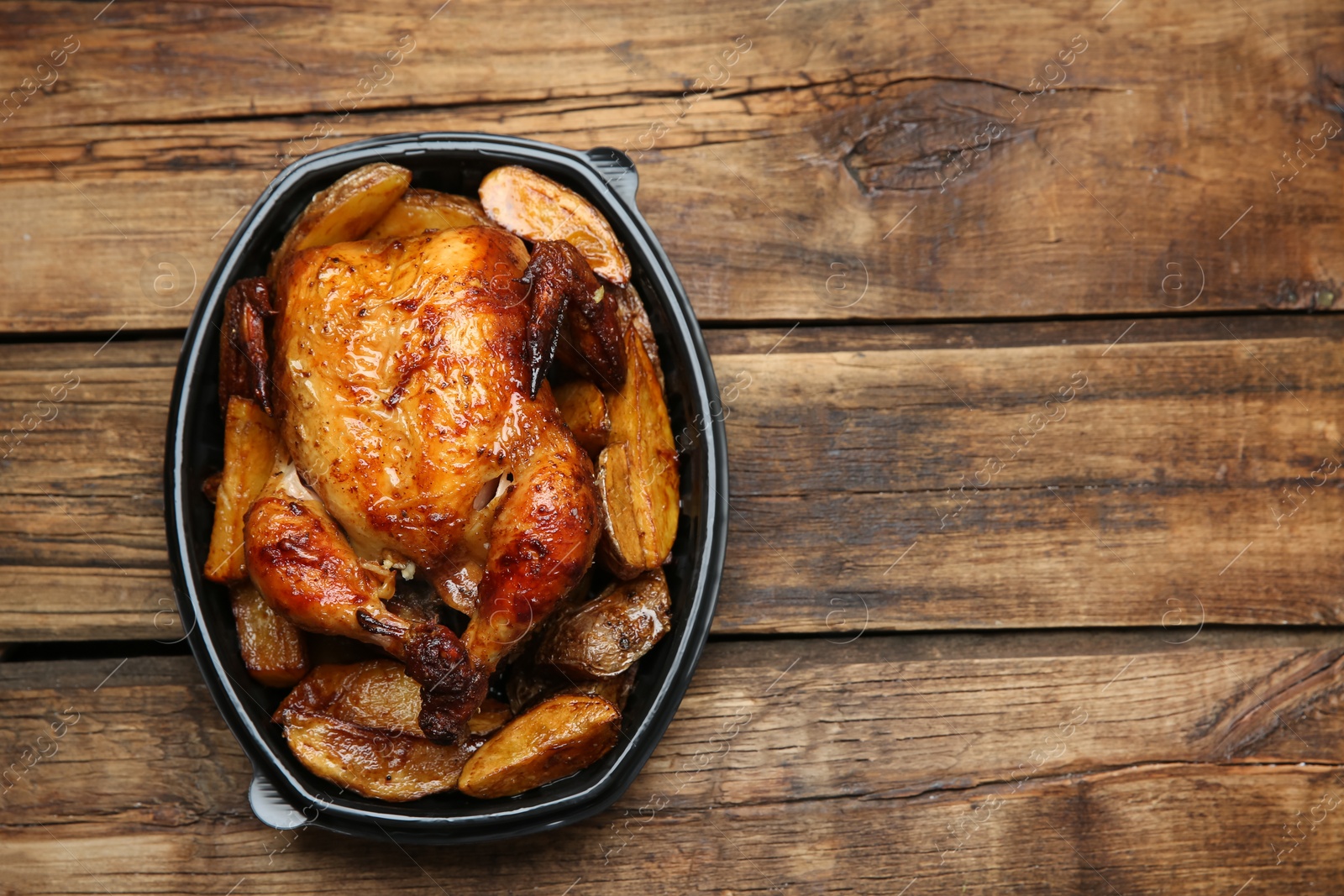 Photo of Top view of delicious grilled chicken with potato in plastic container on wooden table, space for text. Food delivery service