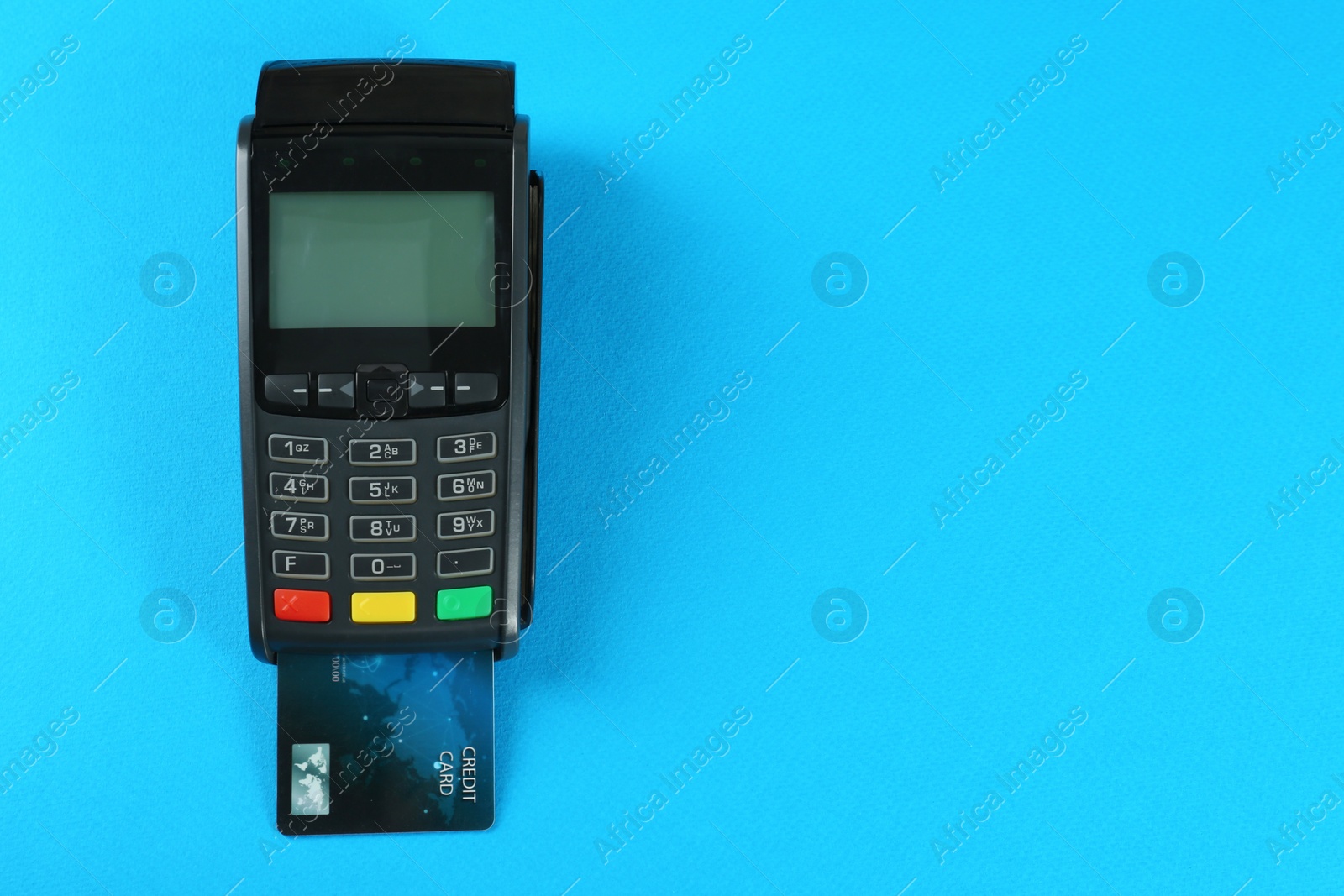 Photo of New modern payment terminal with credit card on light blue background, top view. Space for text