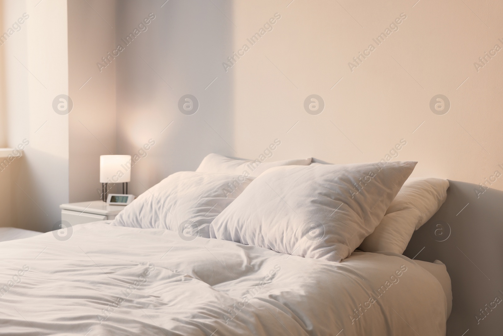 Photo of White soft pillows on bed in room