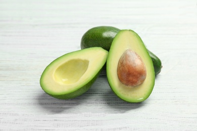 Tasty ripe green avocados on wooden background