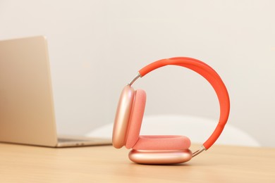 Photo of Modern headphones and laptop on wooden table