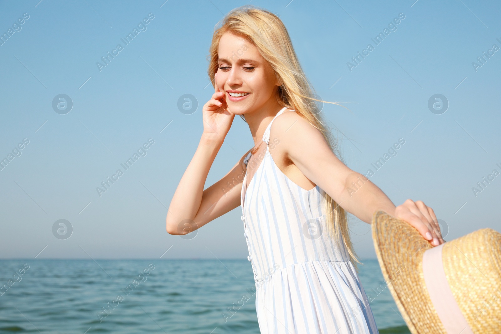 Photo of Beautiful young woman with straw hat near sea on sunny day in summer