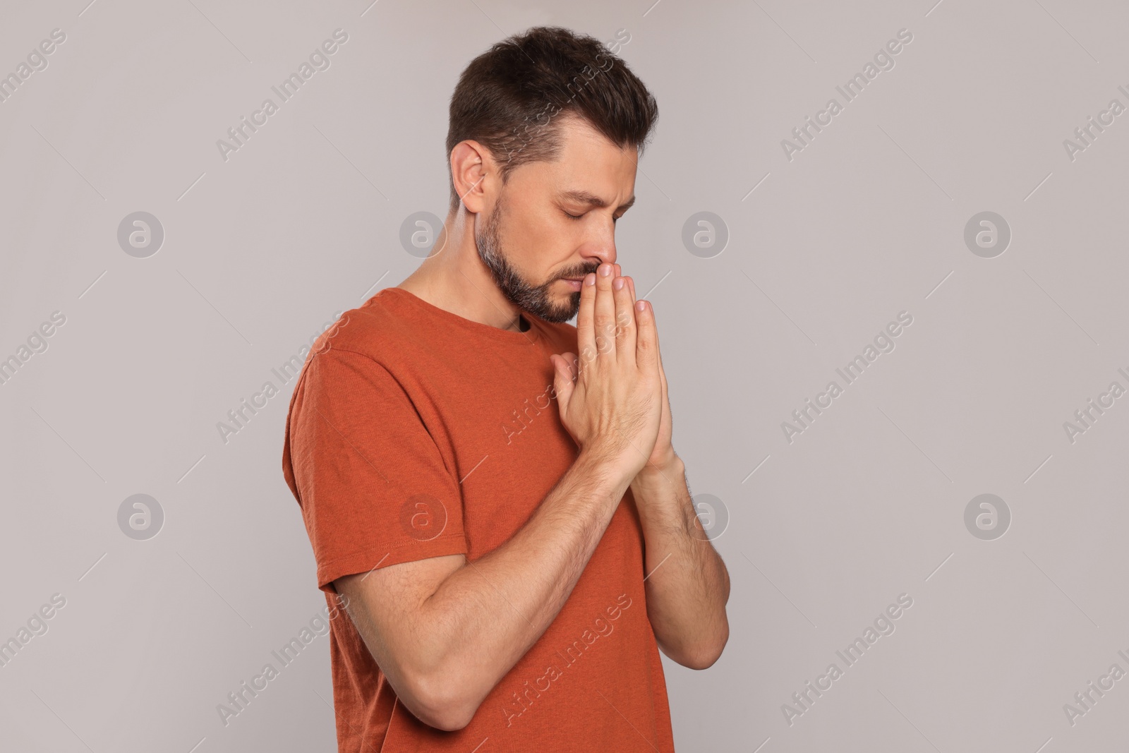Photo of Man with clasped hands praying on light grey background