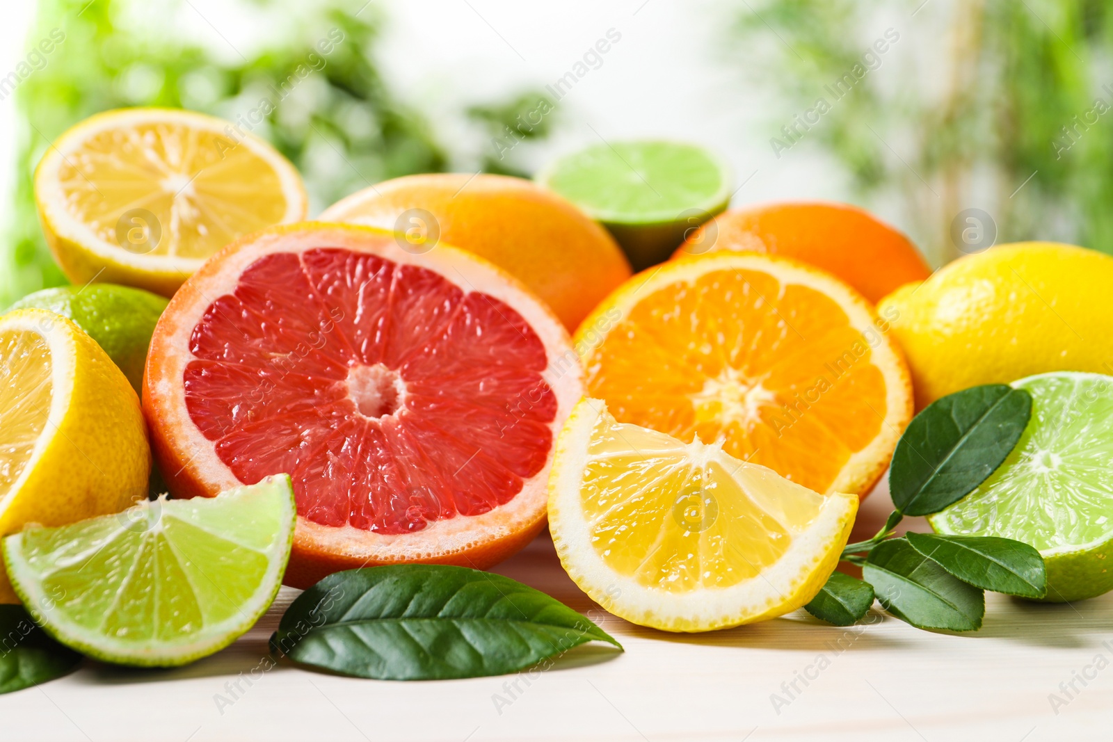 Photo of Different cut and whole citrus fruits on white wooden table, closeup