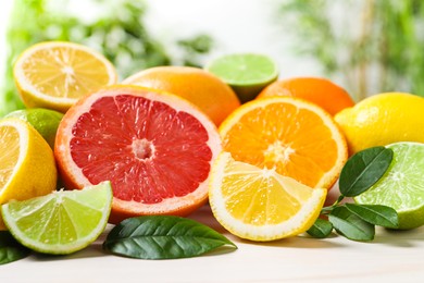 Photo of Different cut and whole citrus fruits on white wooden table, closeup