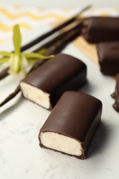 Photo of Glazed curd cheese bars, vanilla pods and flower on white table, closeup