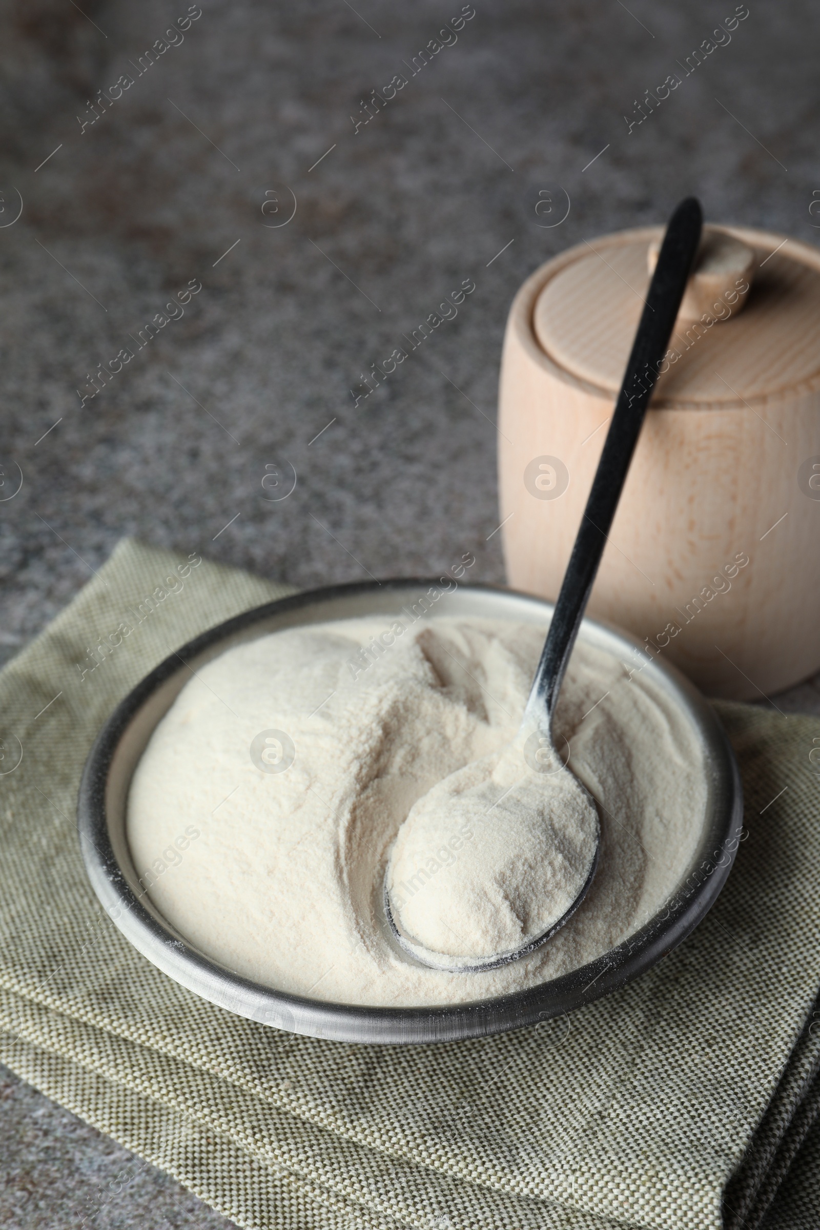 Photo of Bowl, spoon and box of agar-agar powder on grey table