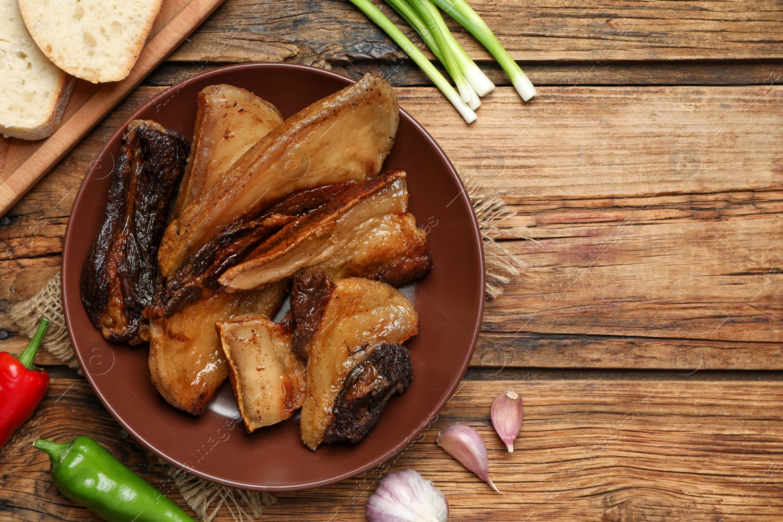 Photo of Tasty fried cracklings on wooden table, flat lay. Cooked pork lard