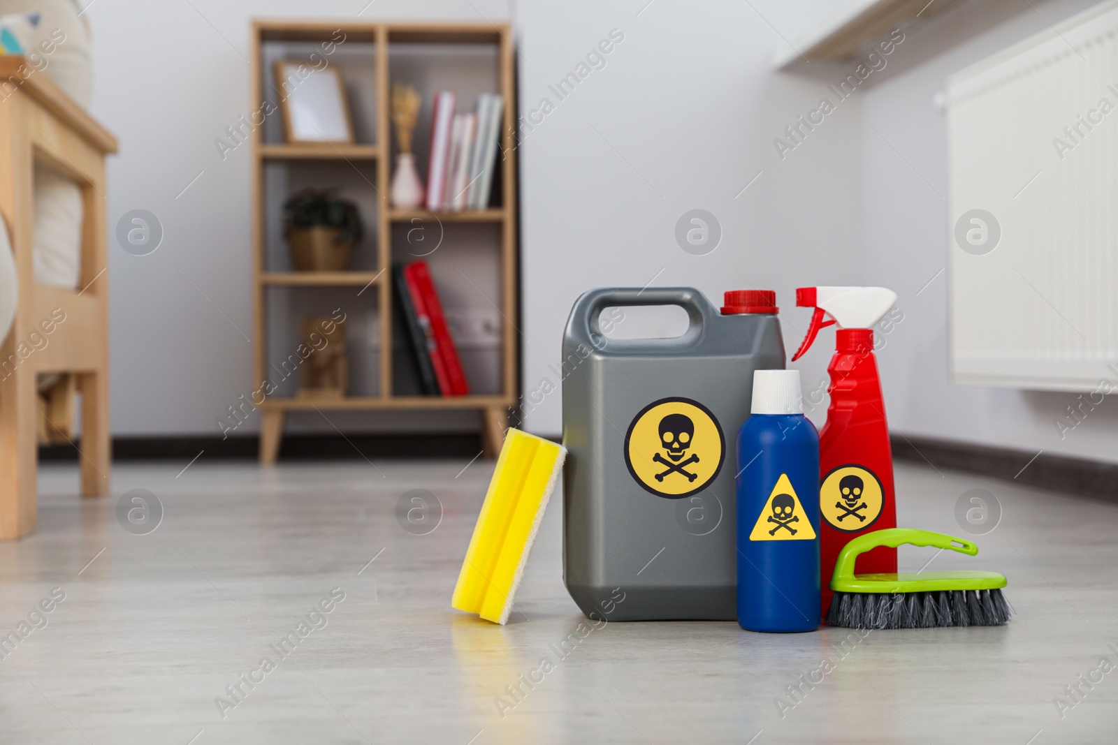 Photo of Bottles of toxic household chemicals with warning signs, brush and scouring sponge in room, space for text