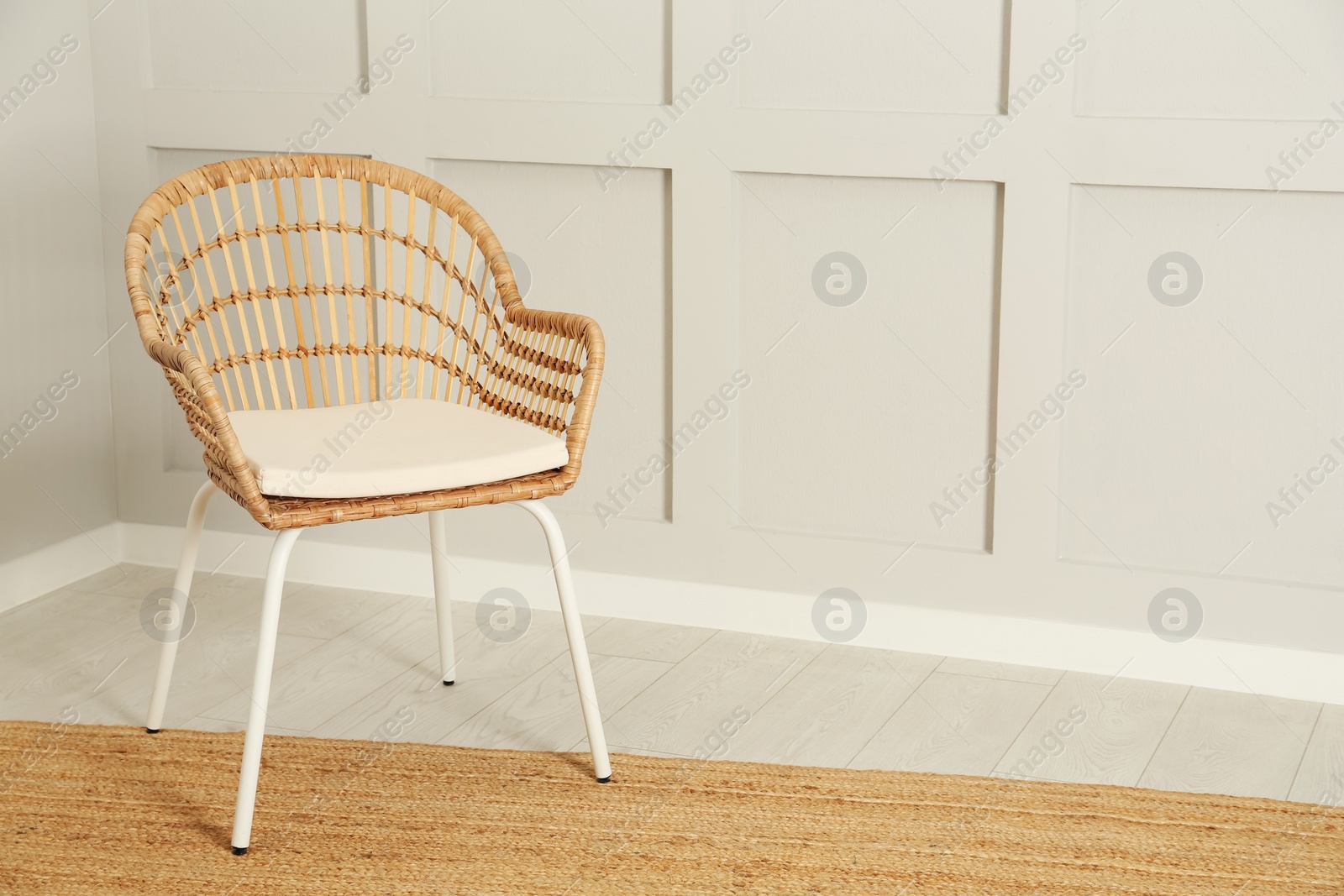 Photo of Stylish wicker armchair near light wall in room. Space for text