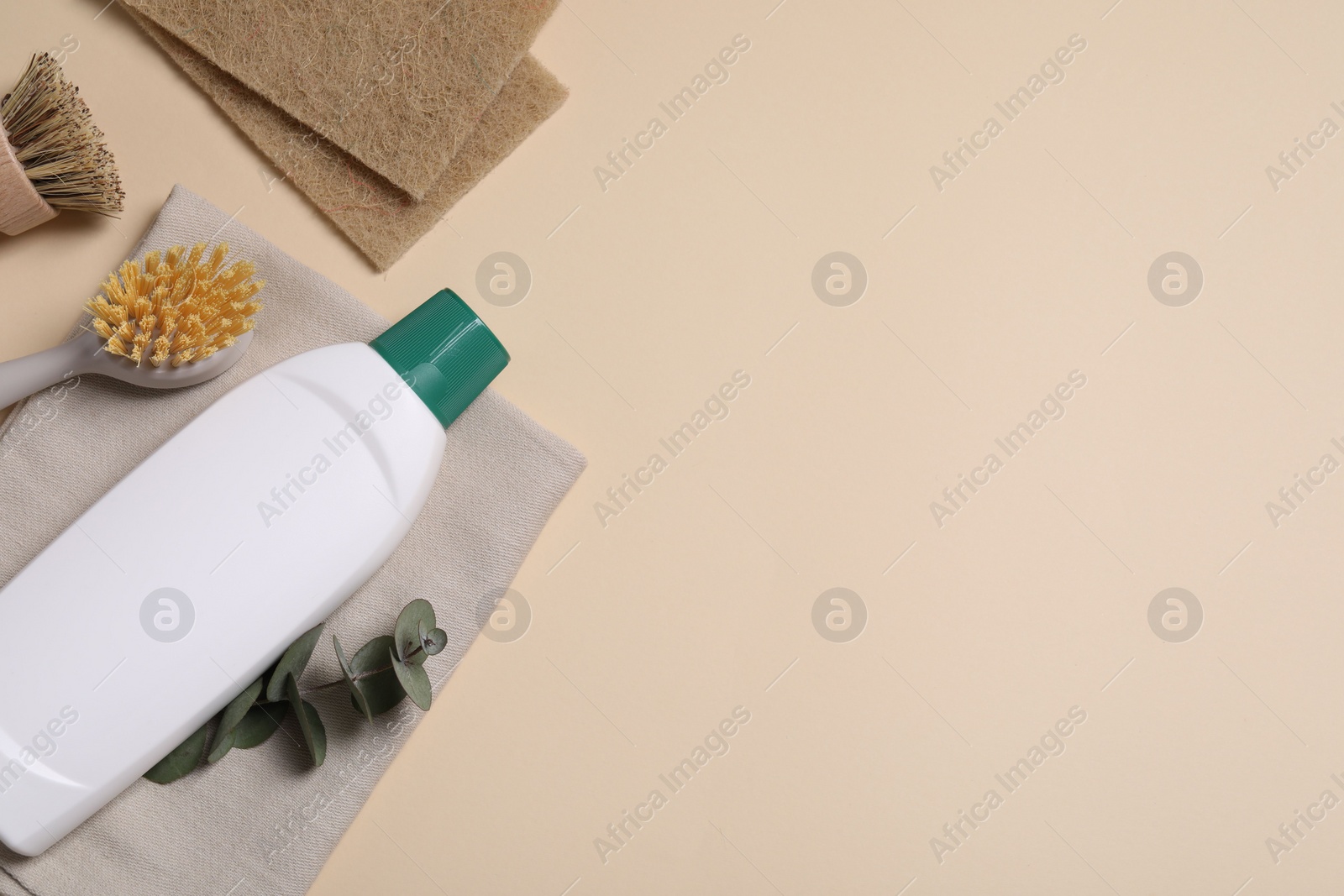 Photo of Bottle of cleaning product, sponges and brushes on beige background, flat lay. Space for text