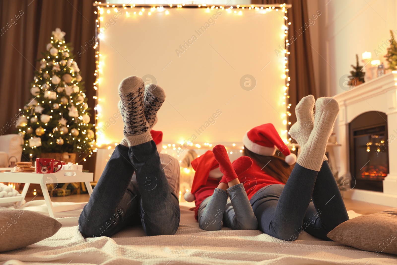 Photo of Family watching movie using video projector at home. Cozy Christmas atmosphere