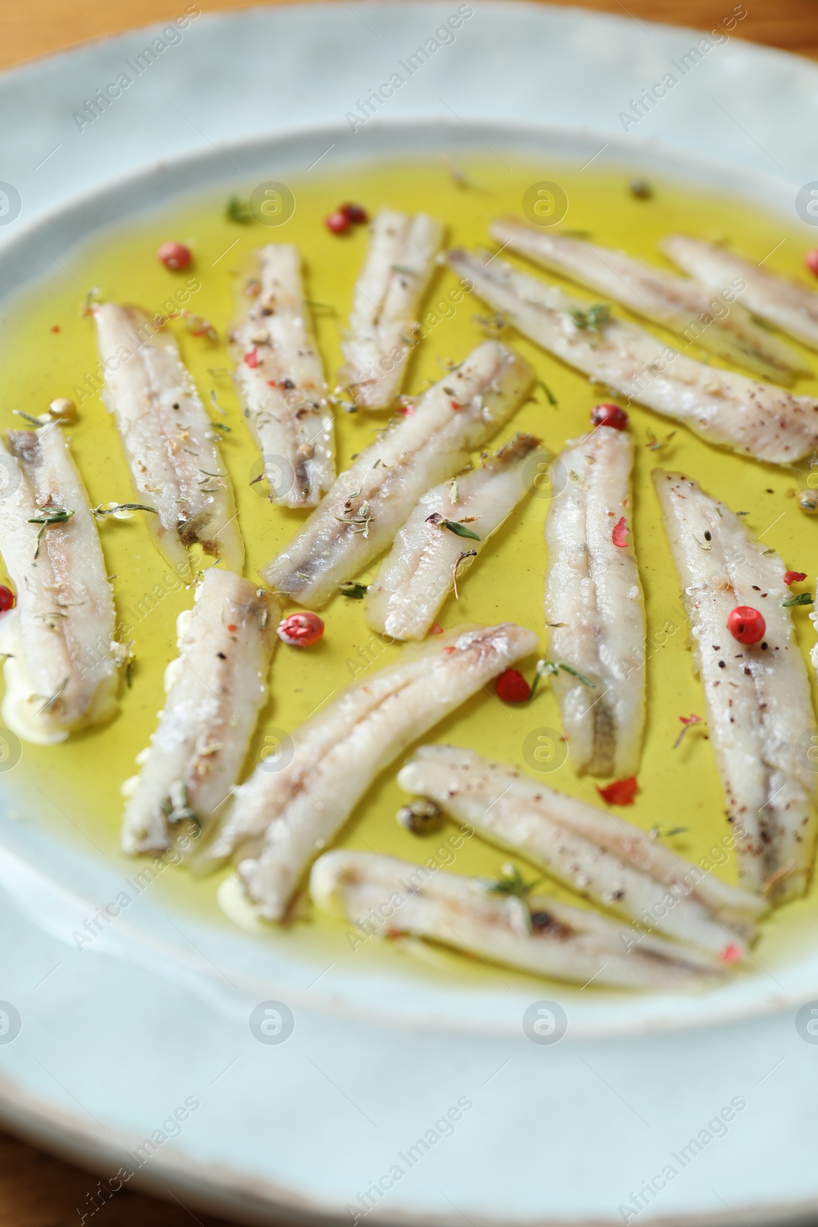 Photo of Tasty pickled anchovies with spices on plate, closeup