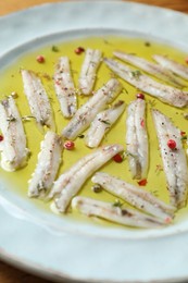 Tasty pickled anchovies with spices on plate, closeup