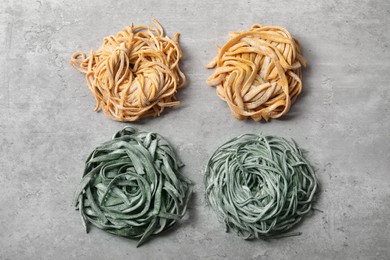 Rolled pasta painted with food colorings on light grey table, flat lay