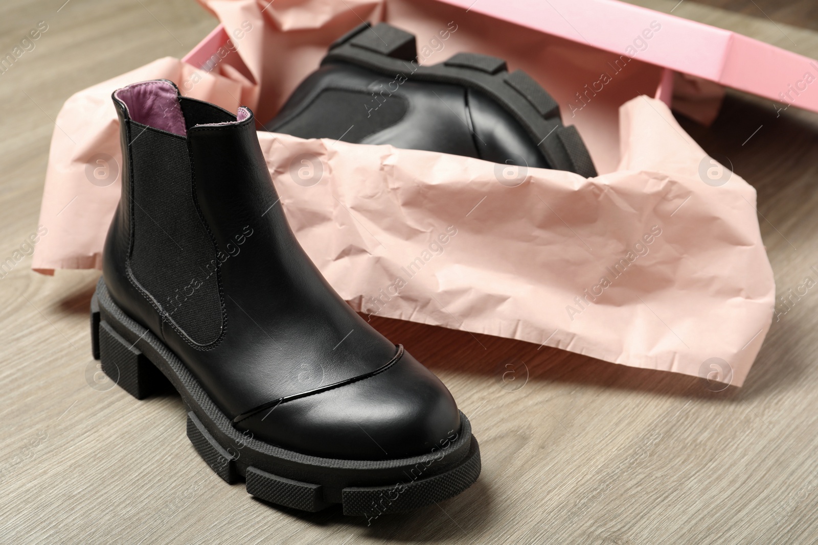 Photo of Pair of stylish boots and box on wooden background