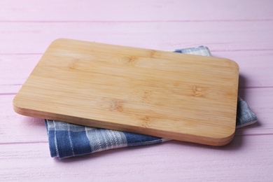 Photo of Kitchen towel and cutting board on pink wooden table