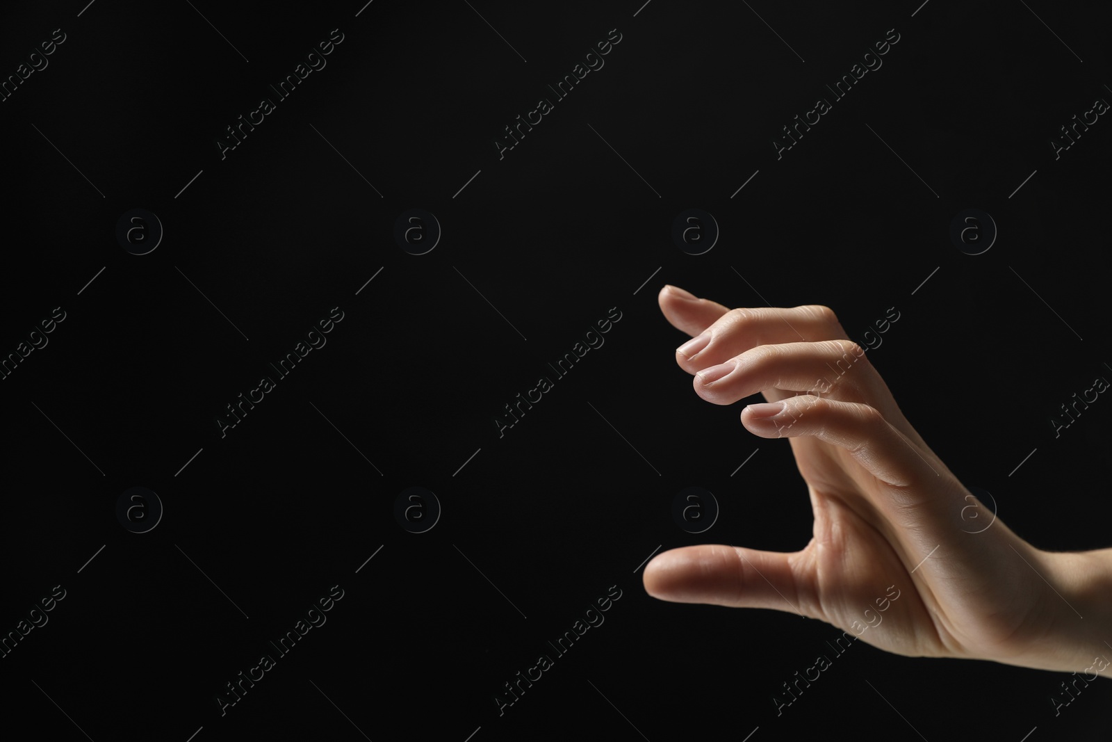 Photo of Woman holding something in hand on black background, closeup. Space for text