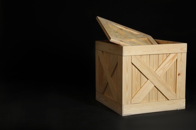 Photo of Wooden crate on black background. Space for text