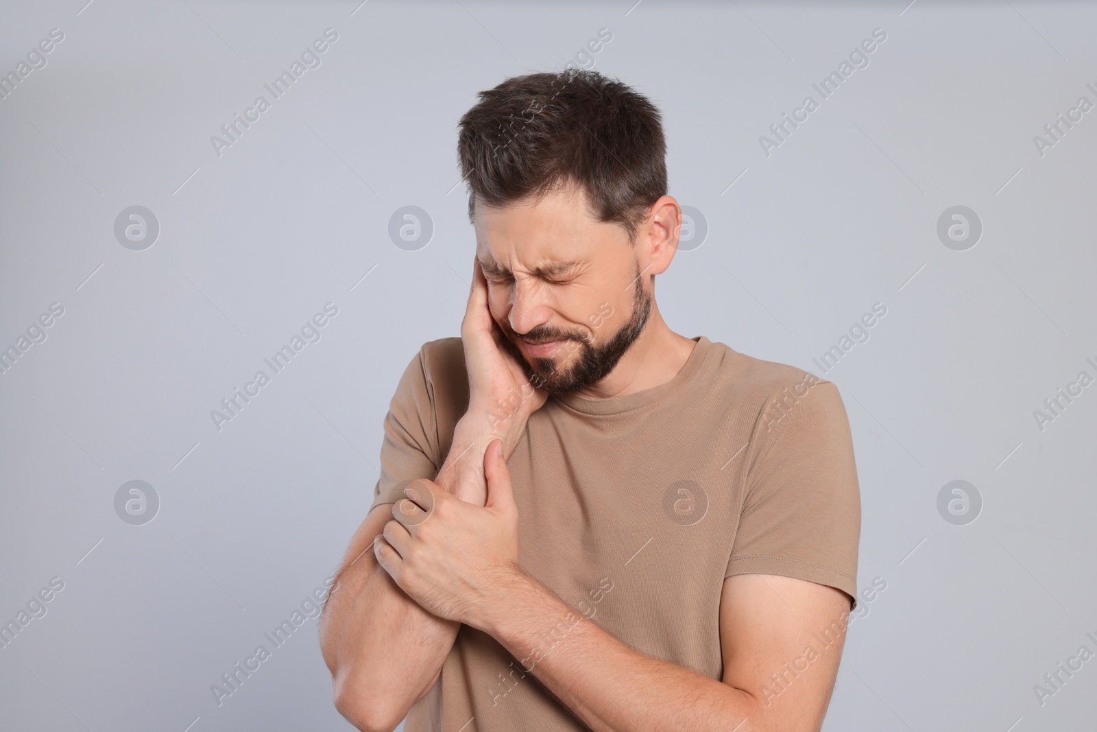 Photo of Man suffering from ear pain on grey background