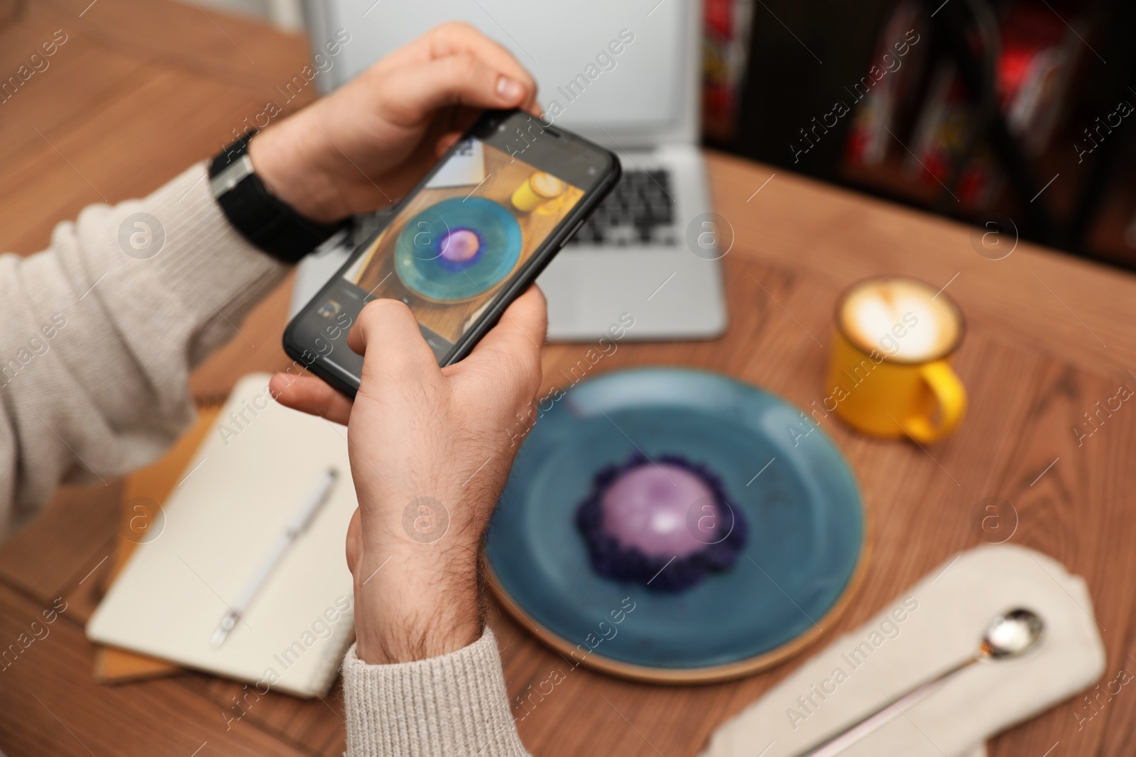 Photo of Male blogger taking photo of dessert and coffee at table in cafe, closeup