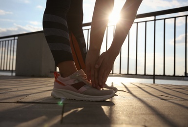 Photo of Young woman stretching on pier near river in morning, closeup