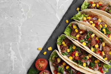 Photo of Delicious tacos with meat and vegetables on light gray marble table, top view. Space for text