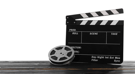 Photo of Movie clapper and film reel on wooden table against white background, space for text