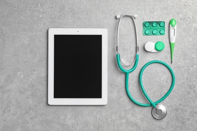 Photo of Tablet with space for text and medical items on gray background, flat lay