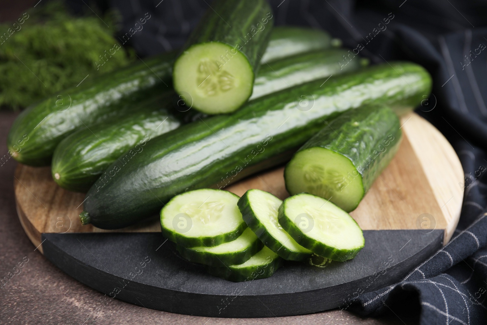 Photo of Fresh whole and cut cucumbers on table, closeup