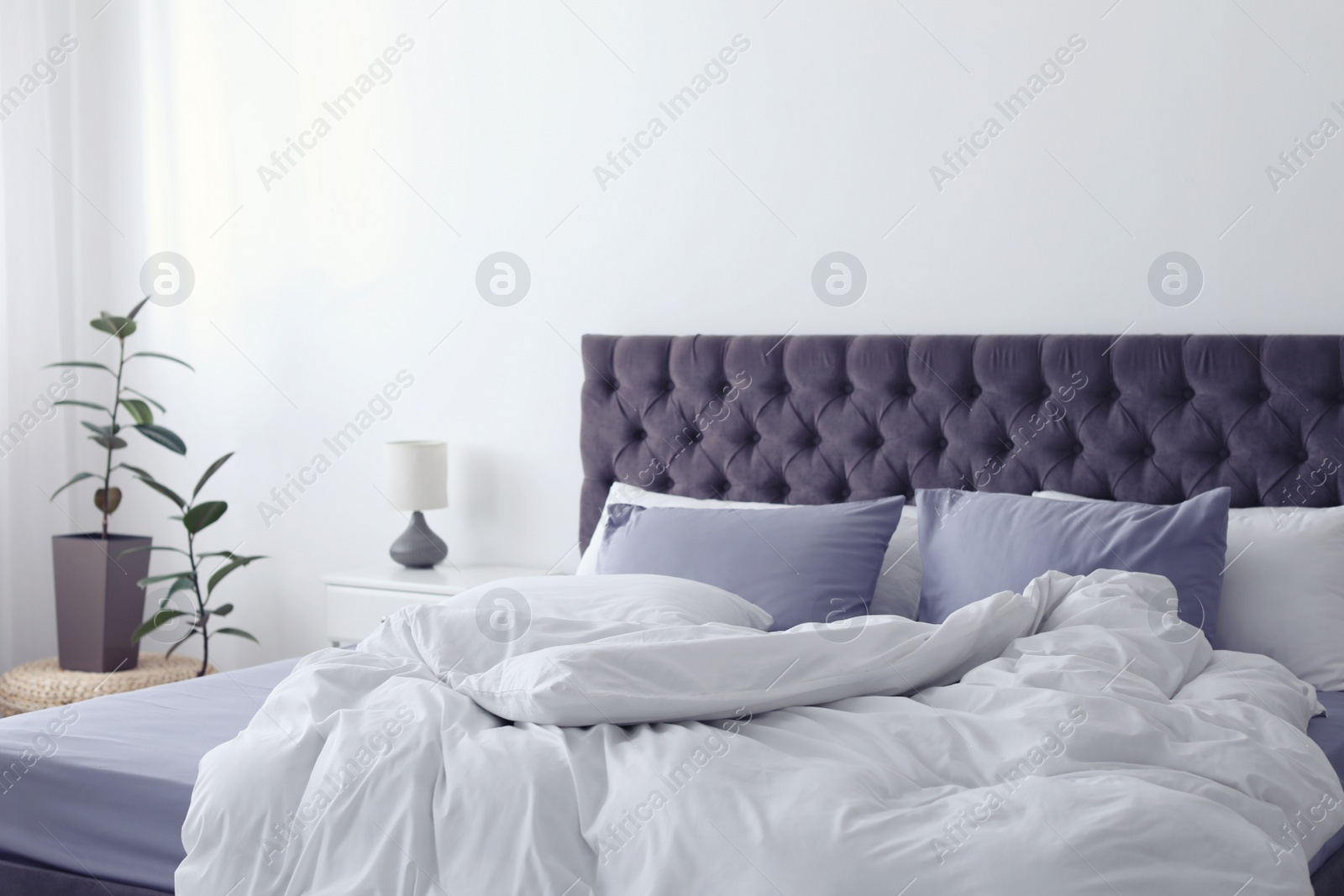 Photo of Modern bed with crumpled blanket and pillows indoors