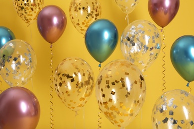 Bright balloons with ribbons on color background