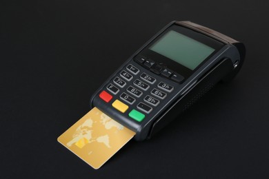 Photo of New modern payment terminal with credit card on black background