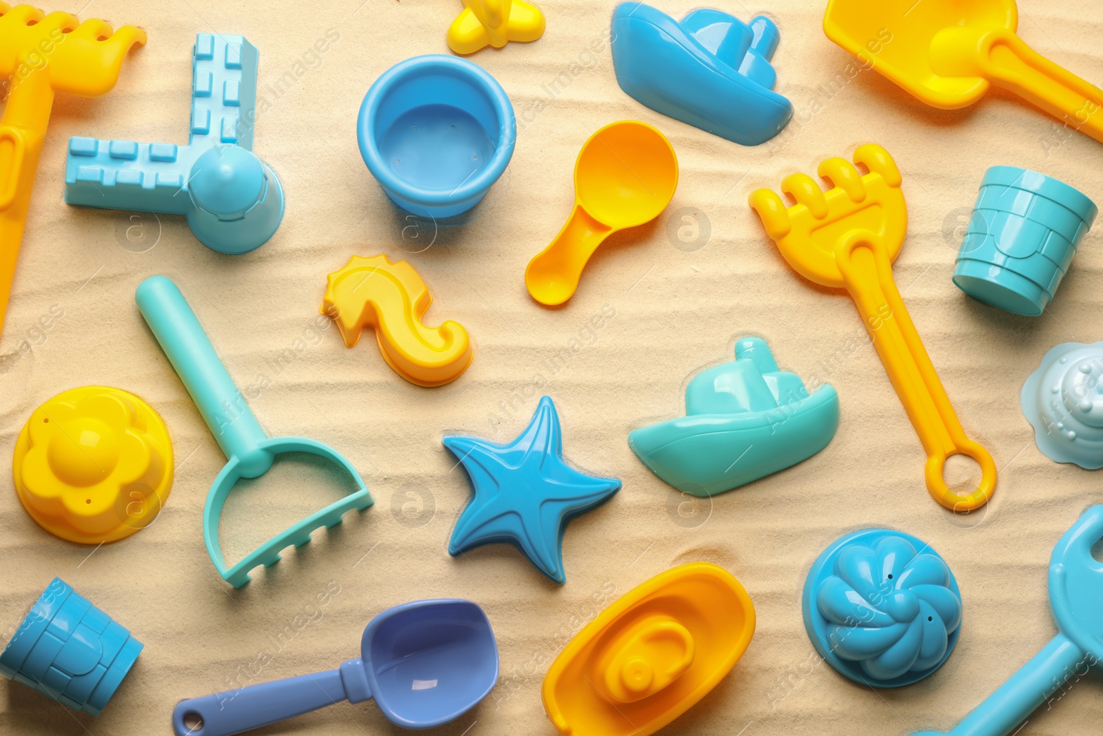 Photo of Beach toy kit on sand, flat lay. Outdoor play