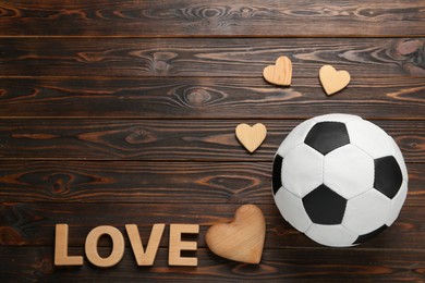 Photo of Soccer ball, hearts and word Love on wooden background, flat lay. Space for text