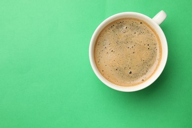 Photo of Aromatic coffee in cup on green background, top view. Space for text