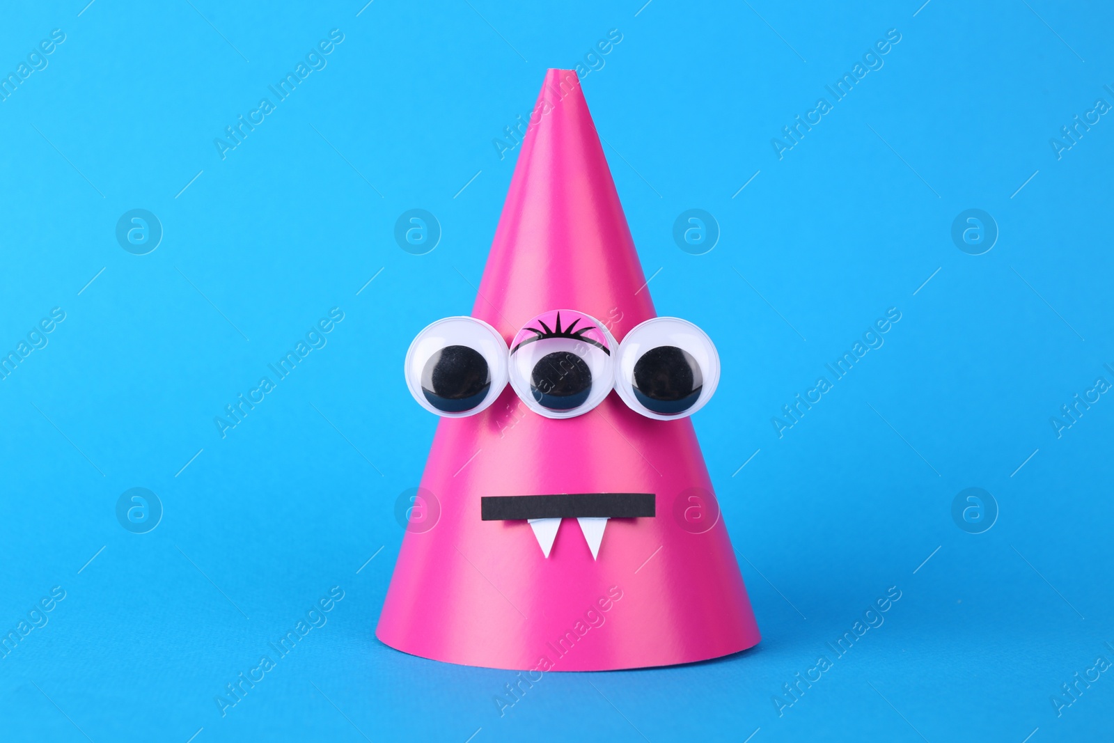 Photo of Spooky paper monster on light blue background. Handmade Halloween decoration