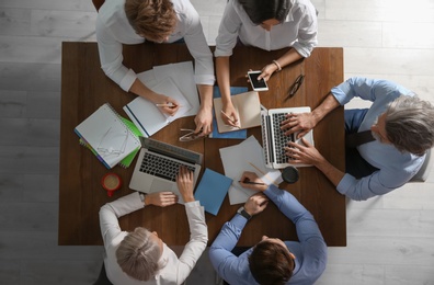 Business people discussing work matters at table in office, top view. Professional communication