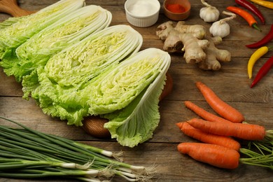 Photo of Cut fresh ripe Chinese cabbages and ingredients on wooden table