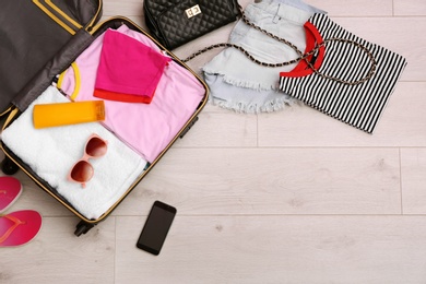 Photo of Packed suitcase on wooden background, top view. Space for text