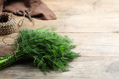 Photo of Bunch of fresh dill on wooden table, space for text