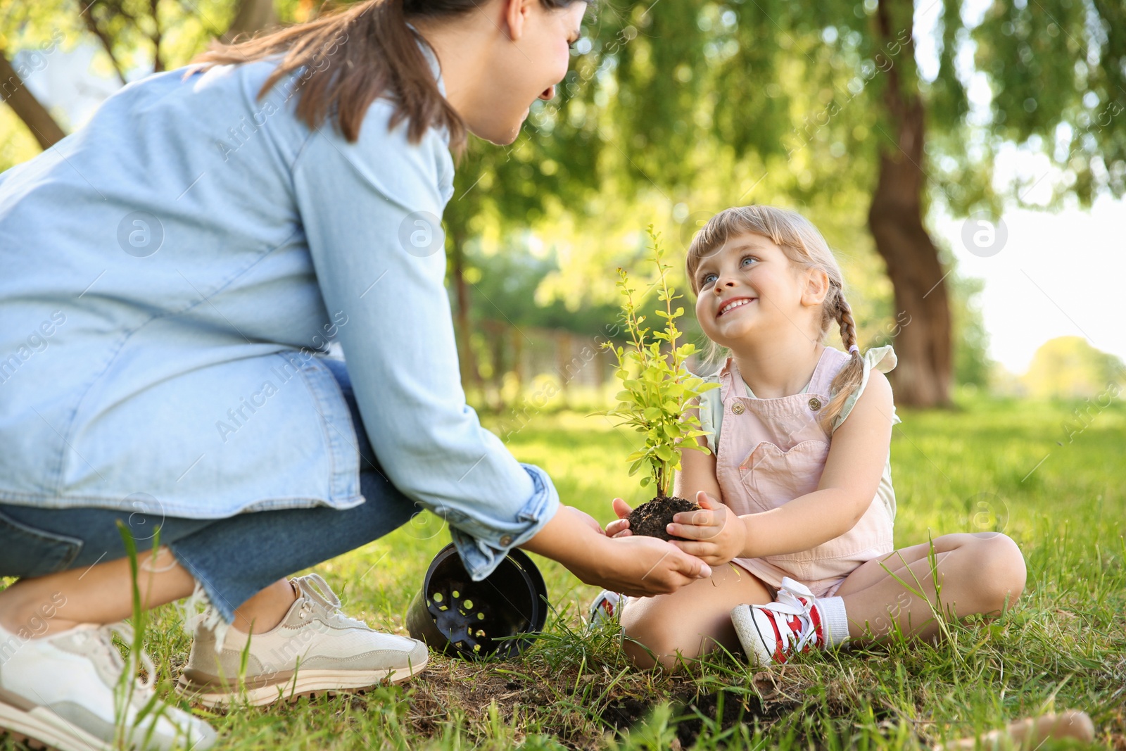 Photo of Mother and her daughter planting tree together in garden