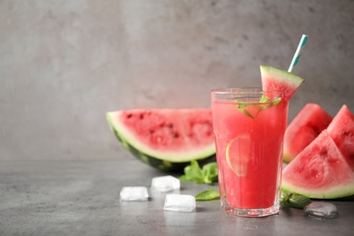 Photo of Glass of tasty refreshing drink with watermelon on grey table. Space for text