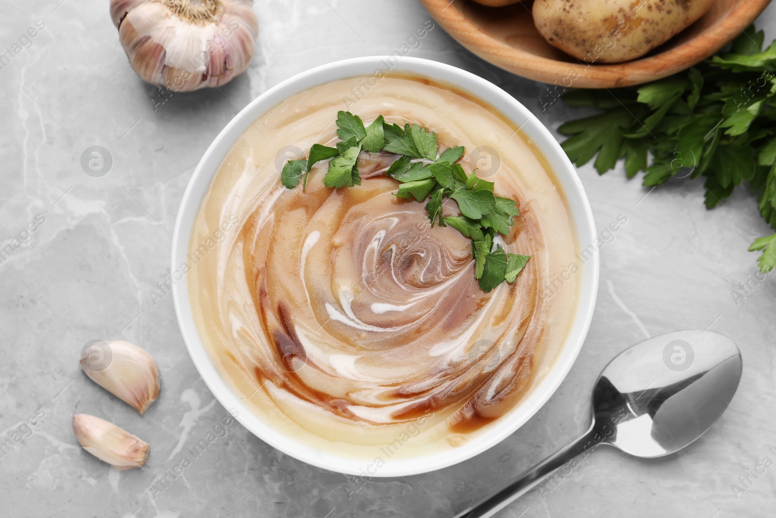 Photo of Delicious cream soup with soy sauce and parsley served on light grey marble table, flat lay