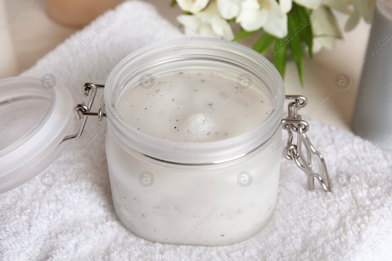 Photo of Jar of natural exfoliating salt scrub on white towel