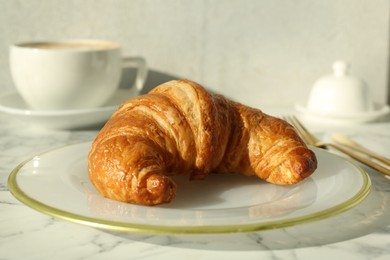 Delicious fresh croissant on white marble table, closeup