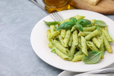 Photo of Delicious pasta with pesto sauce and basil on light grey table, closeup. Space for text