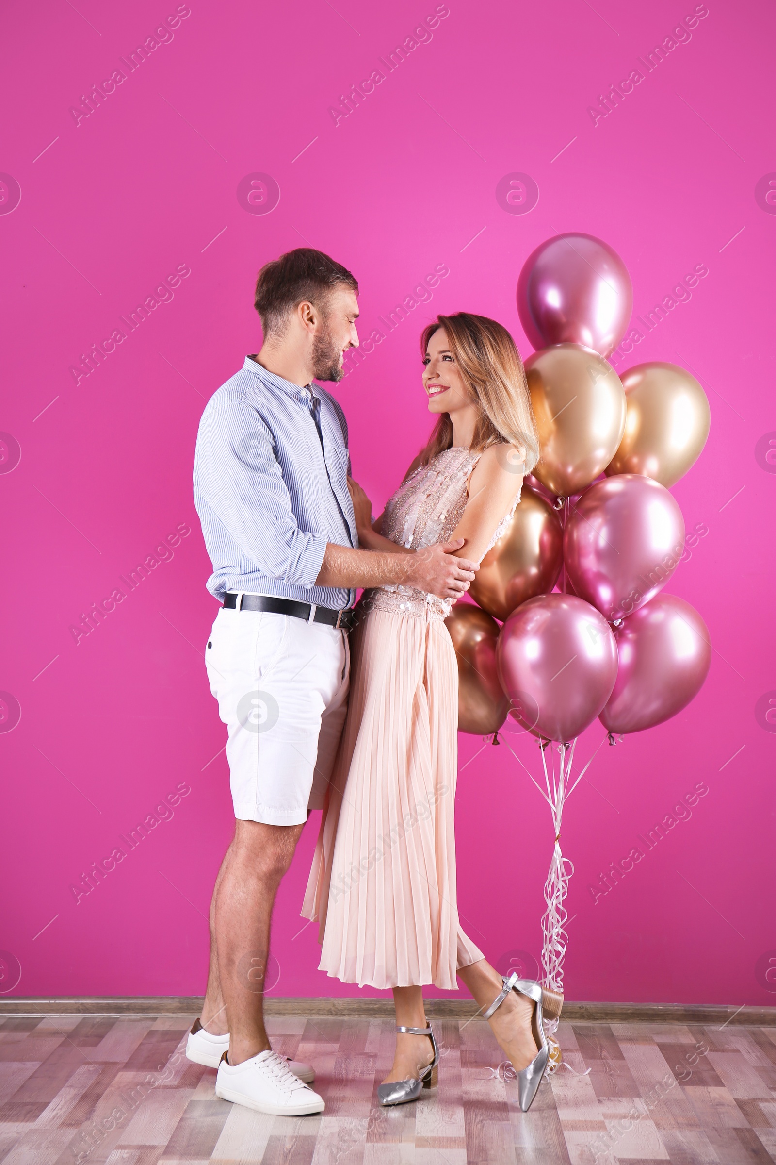 Photo of Young couple with air balloons near color wall