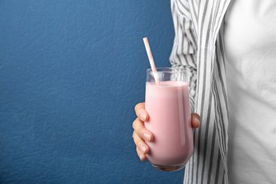 Woman with glass of tasty smoothie on blue background, closeup. Space for text 